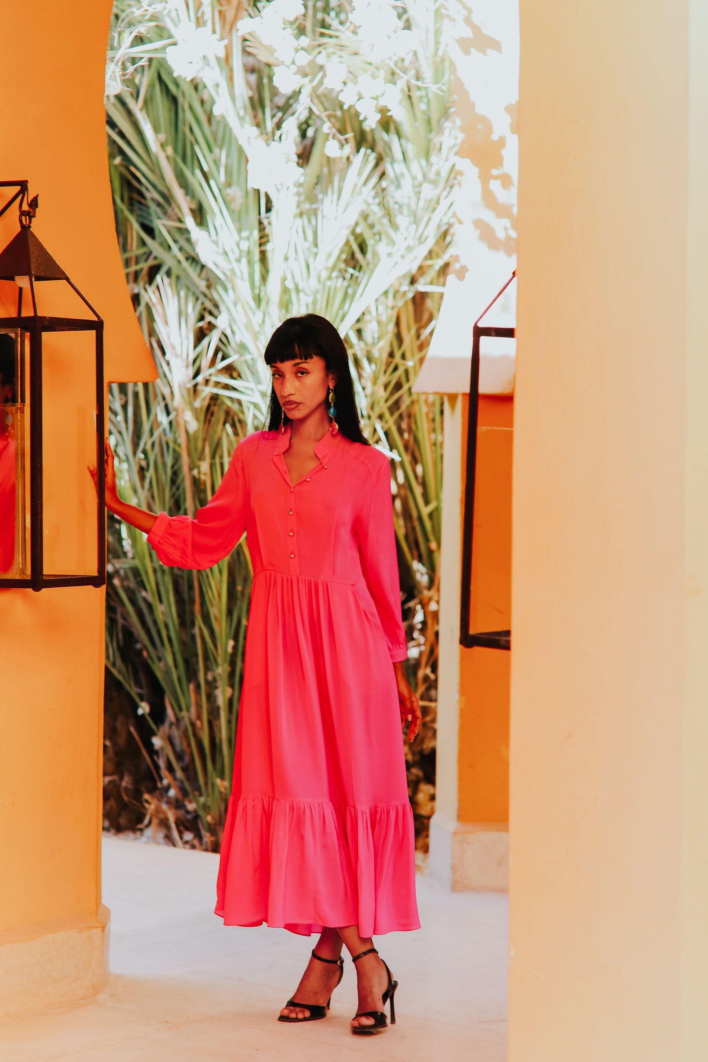 Model wearing pink silk midi dress with three-quarter sleeves