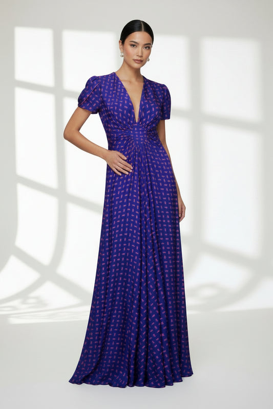 A floor-length purple maxi dress with a small geometric  arrow pattern, short petal sleeves, and a V neckline with a bright pink inner lining, shown against a plain white background.
