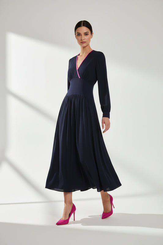 A long-sleeve navy maxi dress with a wrap-style V-neckline accented by bright pink piping, shown against a plain white background.