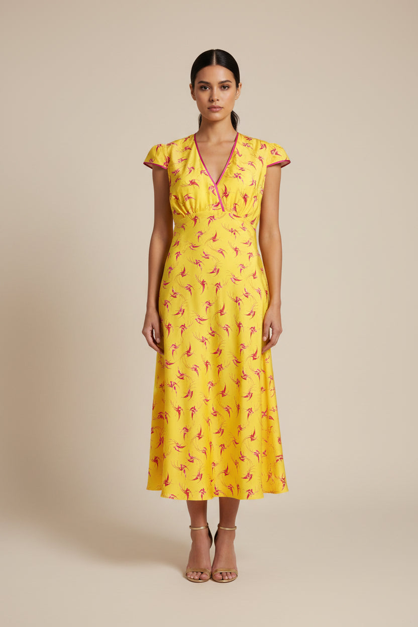 A yellow midi dress with a red and pink lovebird  print, featuring a V-neckline with pink trim and short cap sleeves.